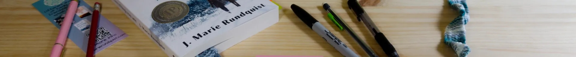 Heavily cropped image of a book laid out on a desk with pens, bookmarks, and post-it notes.