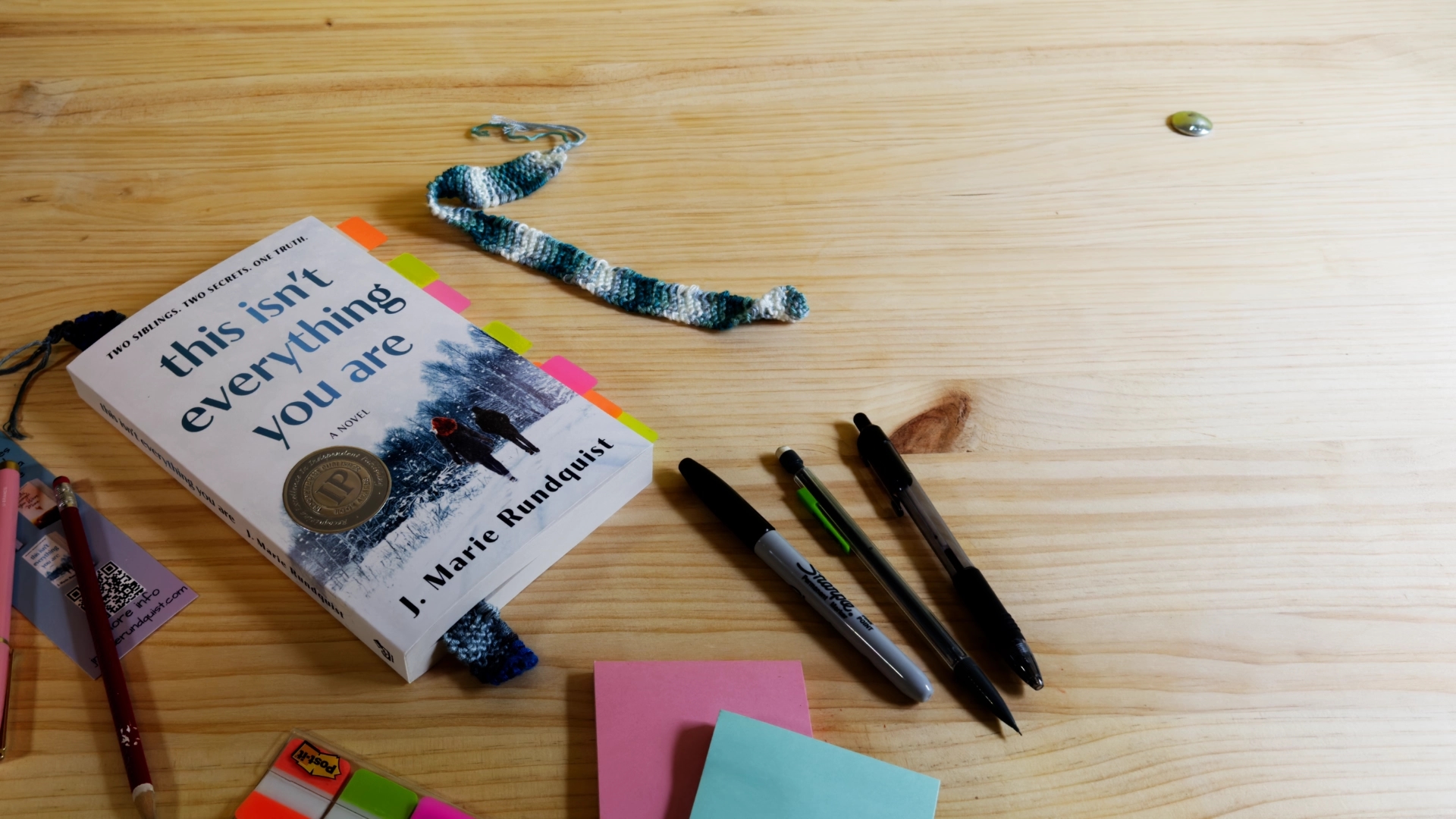 "This Isn't Everything You Are" laid out on a desk, surrounded by pens and post-it notes.